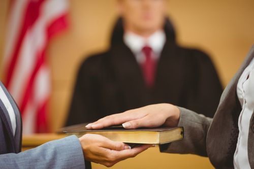 The role of an expert witness with a hand on the bible in court.