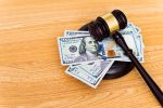 US dollar bills and a gavel on the table. - Dave Burns Law Office, LLC